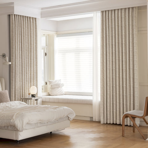 Cortina aislante de lana beige con motivos geométricos.