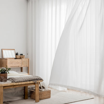 a room with a bed and a white curtain