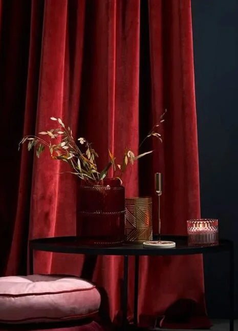 a black table with a pink cushion and a red curtain