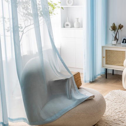 a living room with a white chair and a blue curtain