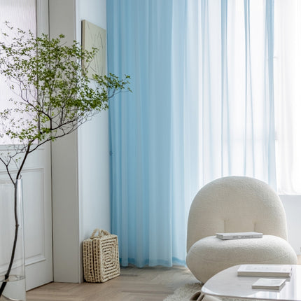 a living room with a white chair and a blue curtain