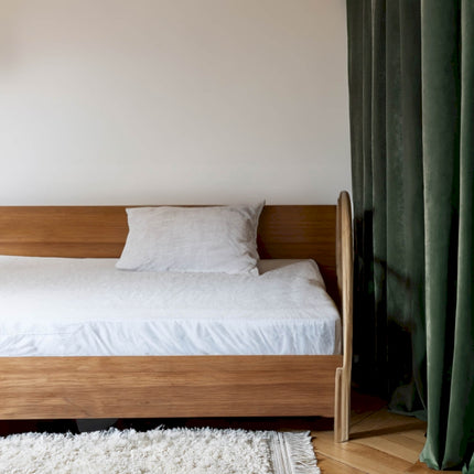 a bed sitting in a bedroom next to a window
