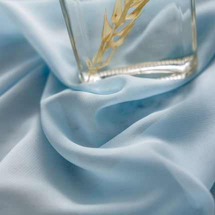 a glass vase with a plant in it on a blue cloth
