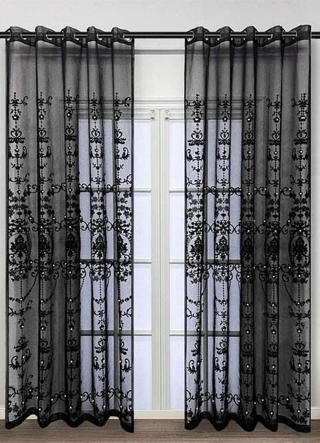 a living room with a window covered in black sheer curtains