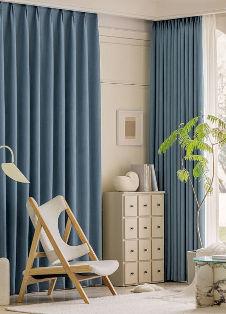 a living room with blue curtains and a white chair